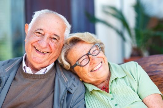 A licensed insurance agent helping an older adult review Medicare Advantage plan options on a laptop.